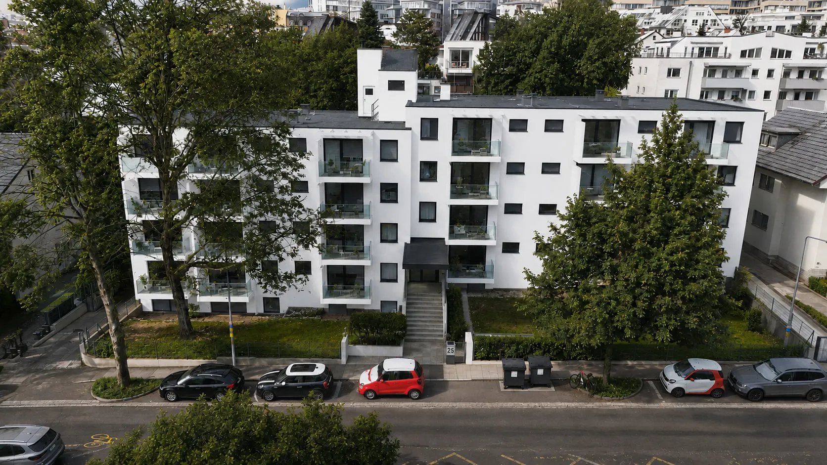 Der Wohnbau SOUTH25 in Schwarzweiß aus der Luft, mit seinen gestaffelten Balkonen zwischen den Bäumen des Grundstücks.